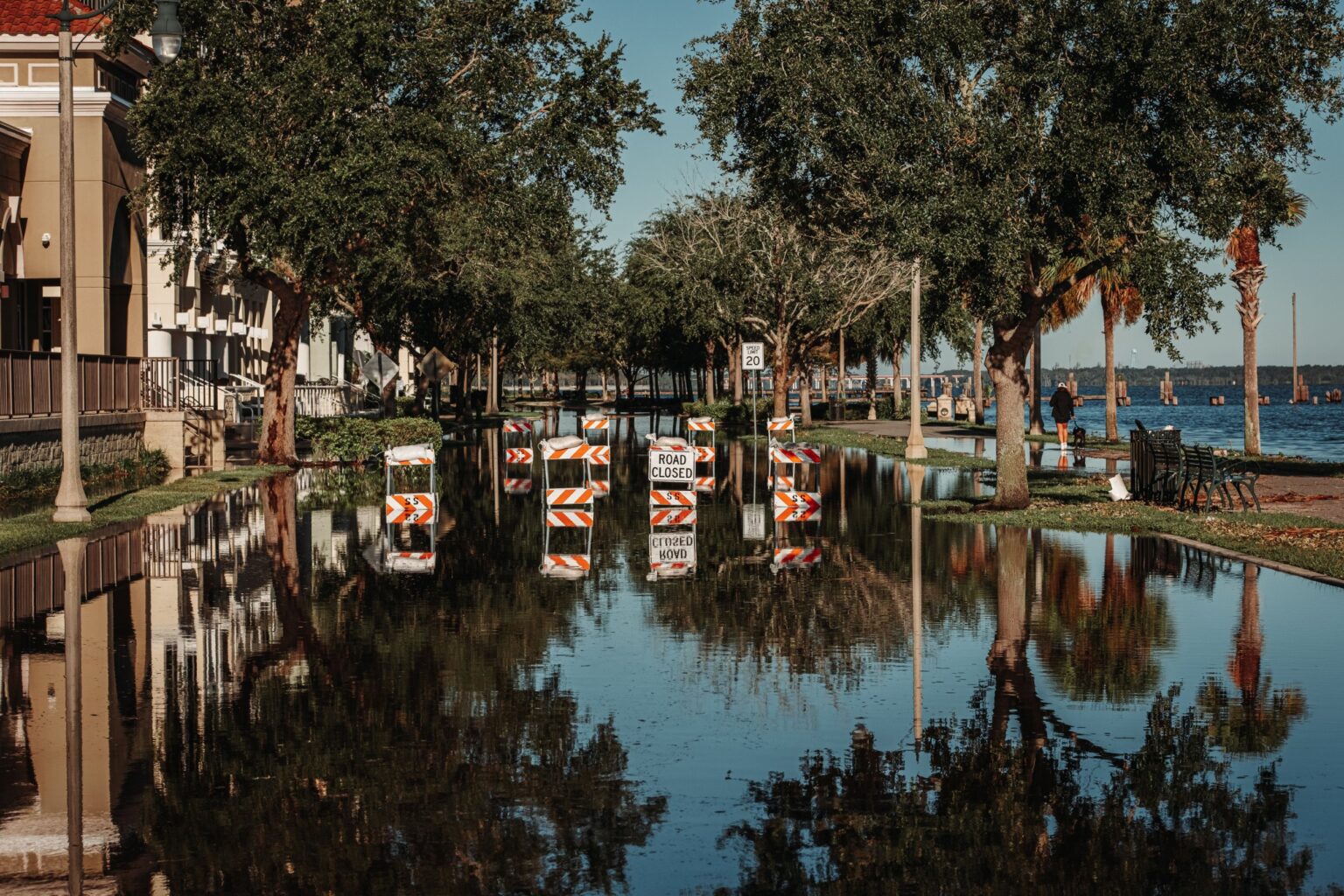 Flooded waterfront street with road-closed barricades after a coastal storm