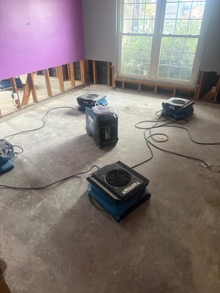 Dehumidifier and air movers drying a bedroom with the lower walls opened
