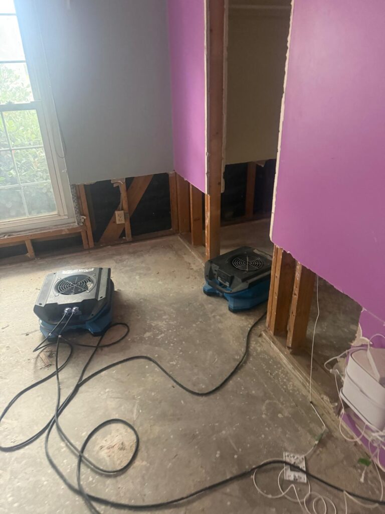 Air movers drying a bedroom corner after water damage
