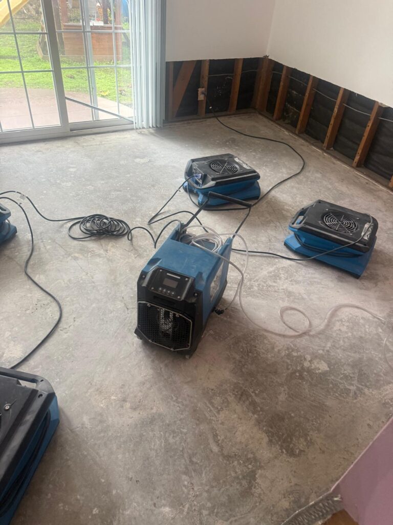 Dehumidifier and air movers set up in a living room after water damage