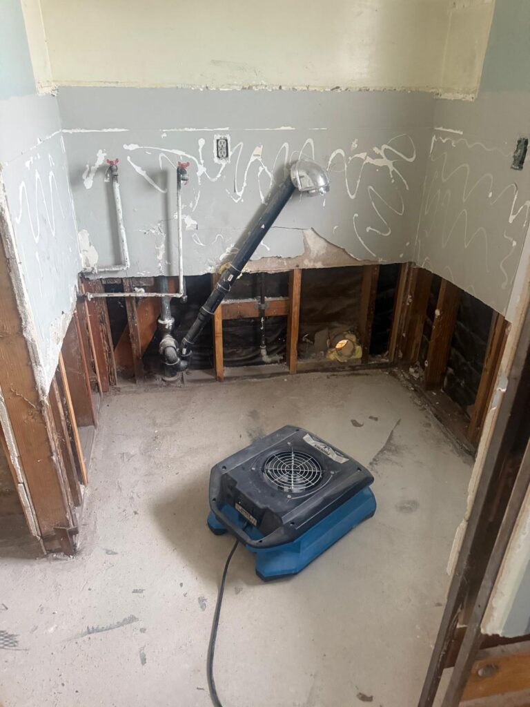 Bathroom vanity wall opened to the studs with an air mover drying the floor