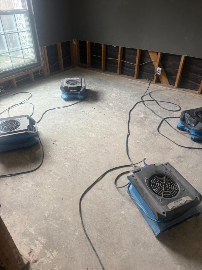 Four air movers drying a room after the damaged drywall was removed