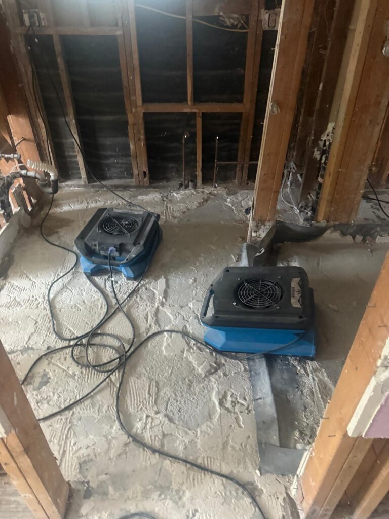Two air movers drying a gutted bathroom after water damage