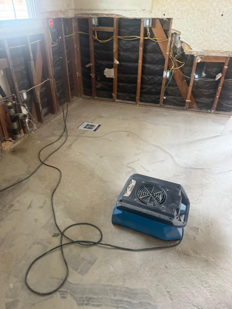 Kitchen walls opened to the studs with an air mover drying the floor