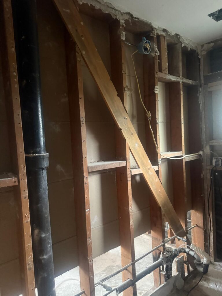 Bathroom wall opened to the framing and plumbing after water damage